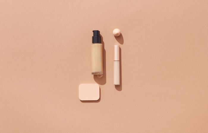 Flat lay of beauty products on a brown background with space for text, ideal for cosmetic promotions.